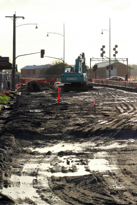 A worker sweeps water off Elgin Boulevard ahead of the strip being covered with asphalt today. Picture: TARA GOONAN