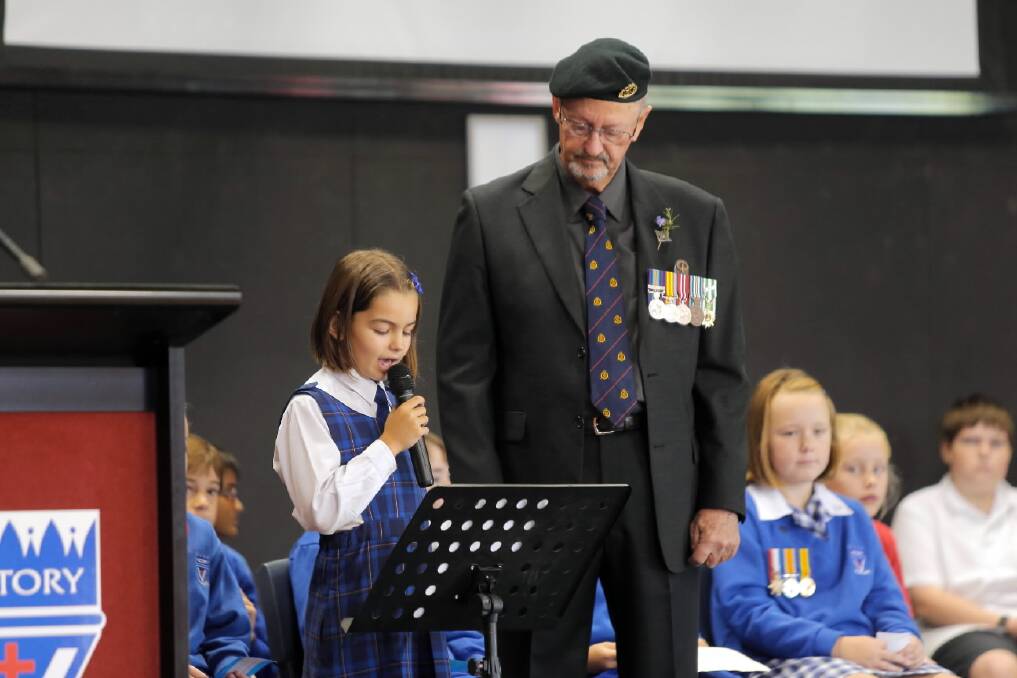 Victory Lutheran College year 3 student Sophie Fothergill, 8, looks up to her grandfather and war veteran Nic Fothergill (above) after singing to him (right) at the school’s Anzac service yesterday. Pictures: TARA GOONAN