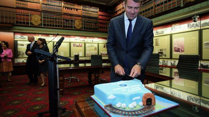 NSW Premier Mike Baird cuts a cake in the shape of NSW for his 47th birthday before a party room meeting of the NSW Liberals on Wednesday. Photo: Kate geraghty