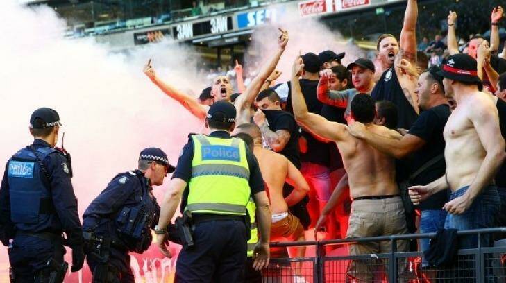 Fired up: Wanderers fans in the crowd let off flares as police officers look on during Saturday's match at  Etihad Stadium. Photo: Scott Barbour/