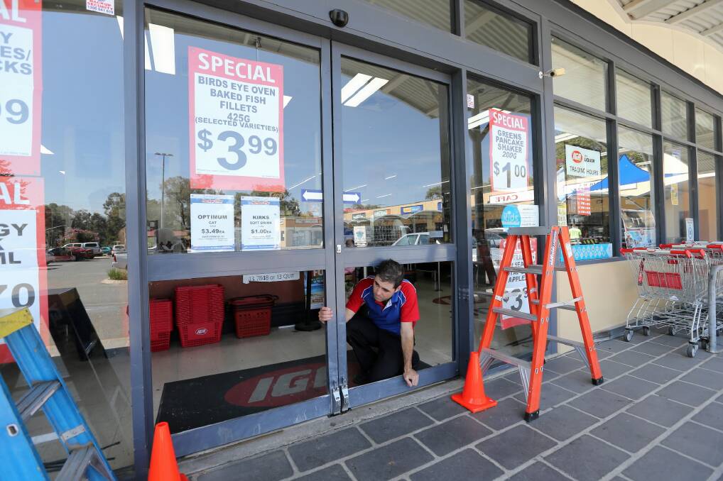 Jindera IGA Supermarket manager John Paul Mathews looks through the missing glass panels from the front door that was ram-raided late on Thursday. Picture: PETER MERKESTEYN