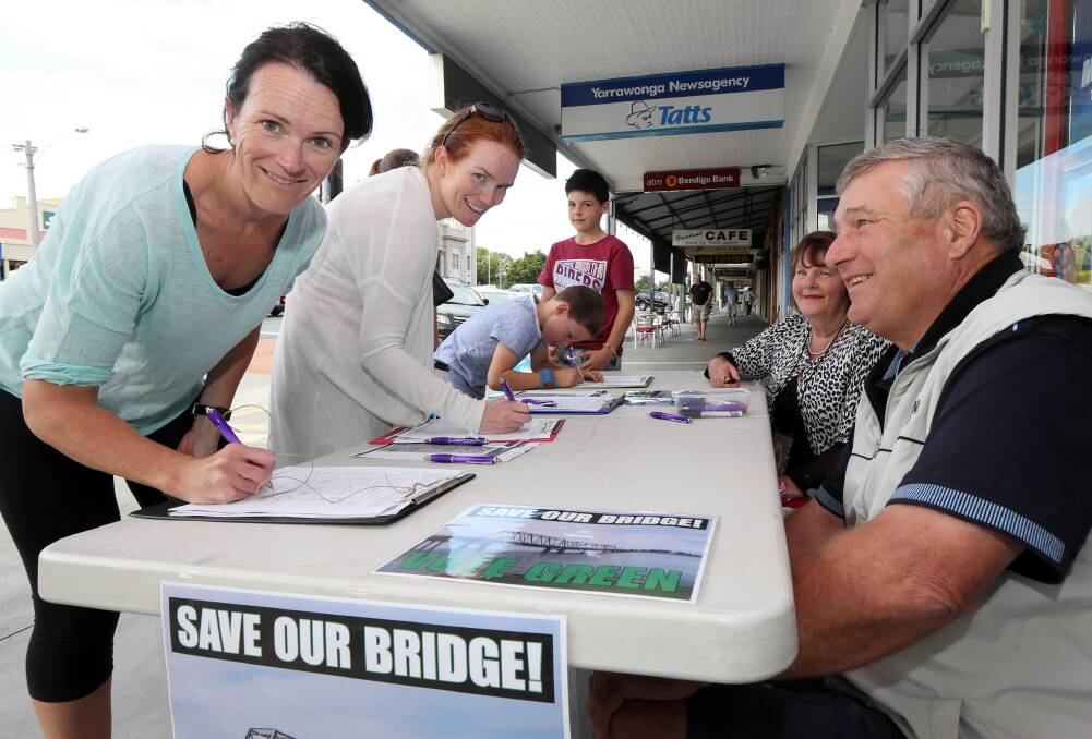 Yarrawonga resident Sonia Bourke signs the petition calling for the retention of the existing bridge for pedestrians. Annie O’Donnell and John Lawless were taking names. Picture: PETER MERKESTEYN