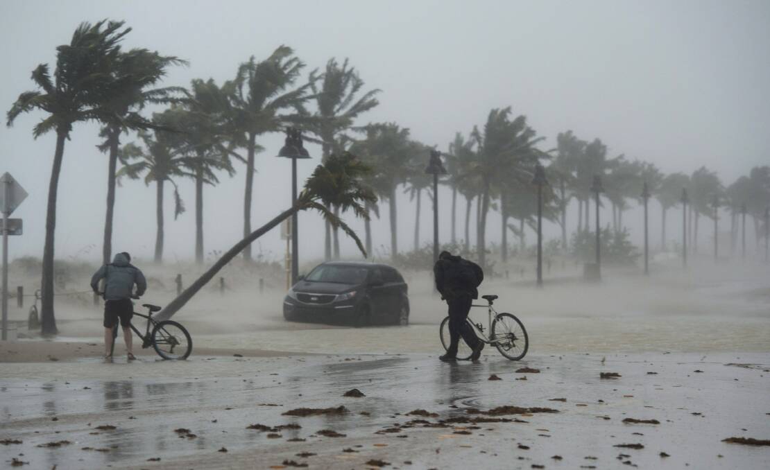 Two men walk their bicycle along a flooded street on the waterfront of Fort Lauderdale, Fla., as Hurricane Irma passes through on Sunday, Sept. 10, 2017. Picture: Paul Chiasson/The Canadian Press via AP