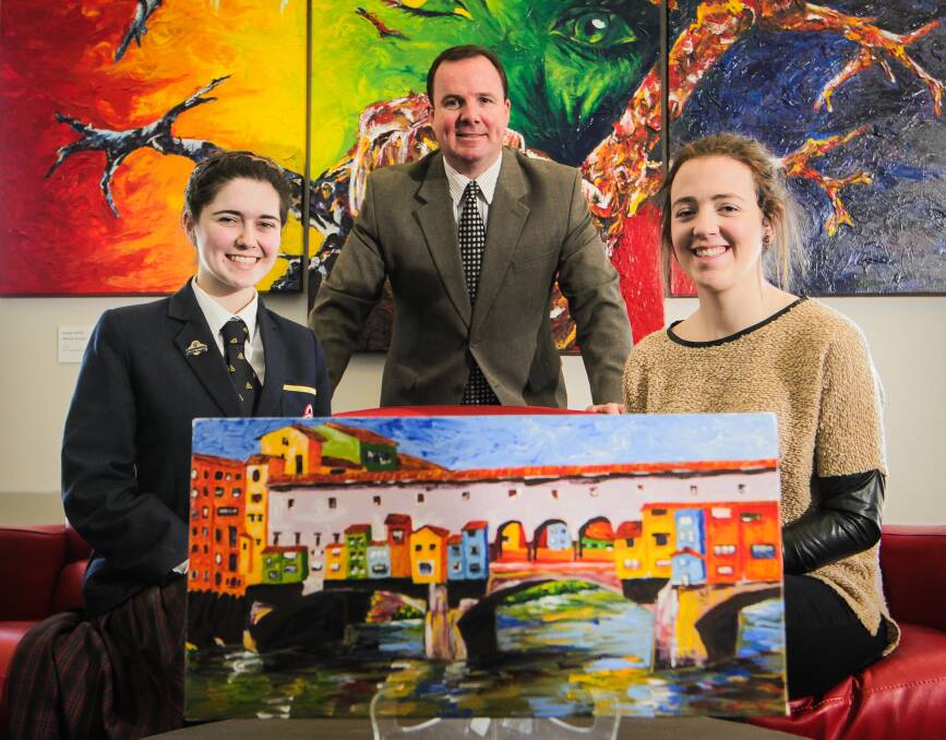 School principal Steven O'Connor and student Natasha Cerexhe with former student and artist Georgie Liston and her painting 'Florence: The Working Bridge one of the exhibits at the Trinity College Arts Exhibition in the Multi-purpose Hall at Trinity College Albury campus, Thurgoona.