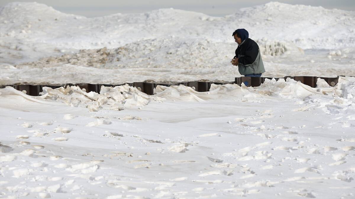 A man walks along a snow covered beach in Chicago, Illinois, January 8, 2014. Photo: REUTERS/Jim Young.