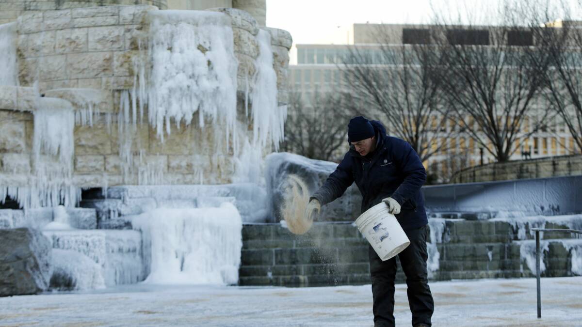 A worker spreads sand near an exterior waterfall that froze overnight at the National Museum of the American Indian in Washington January 7, 2014. Photo: REUTERS/Gary Cameron.