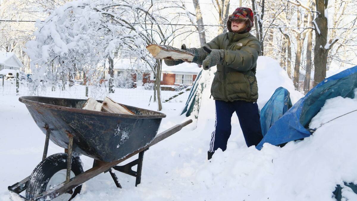 Kim Rogers loads firewood into a wheelbarrow at her home in Indianapolis, Indiana, January 7, 2014. Photo: REUTERS/Brent Smith.