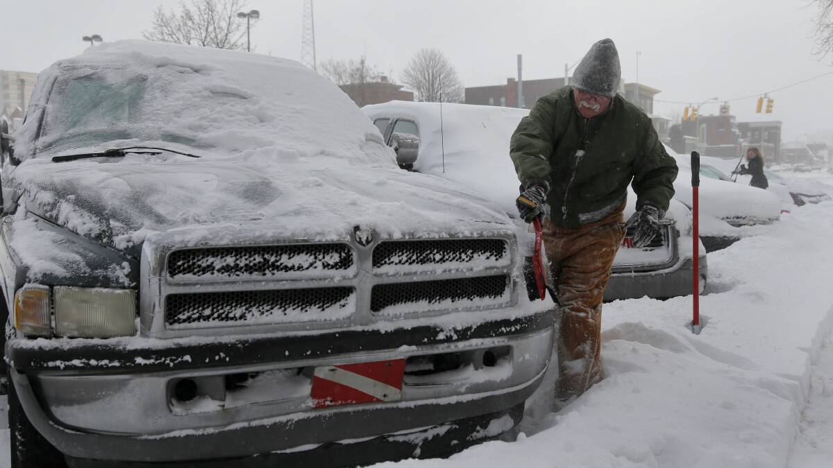 Barry Tilton cleans the snow off of his pick-up truck in the midtown neighborhood of Detroit, Michigan January 6, 2014. Photo: REUTERS/Rebecca Cook.