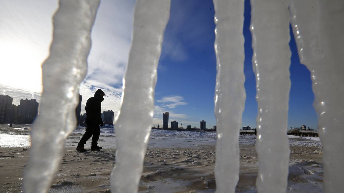 A man is framed by icicles as he walks along a beach in Chicago, Illinois, January 7, 2014. Photo: REUTERS/Jim Young.