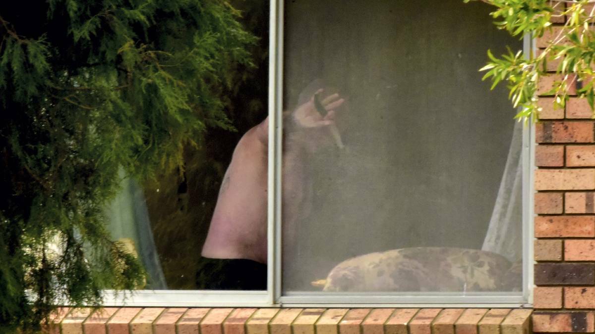 The alleged offender at a window of the Rocherlea home during Tuesday’s 12-hour siege. Picture: NEIL RICHARDSON