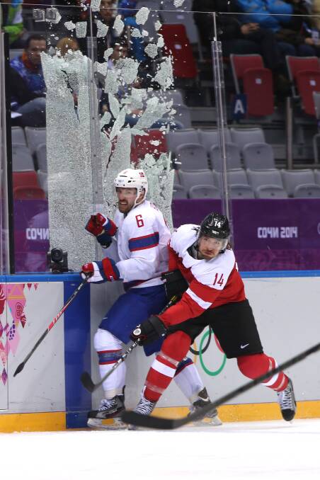 Andreas Nodl #14 of Austria checks Jonas Holos #6 of Norway to break the glass during the Men's Ice Hockey Preliminary Round Group B game on day nine of the Sochi 2014 Winter Olympics at Bolshoy Ice Dome on February 16, 2014 in Sochi, Russia. Photo: GETTY IMAGES