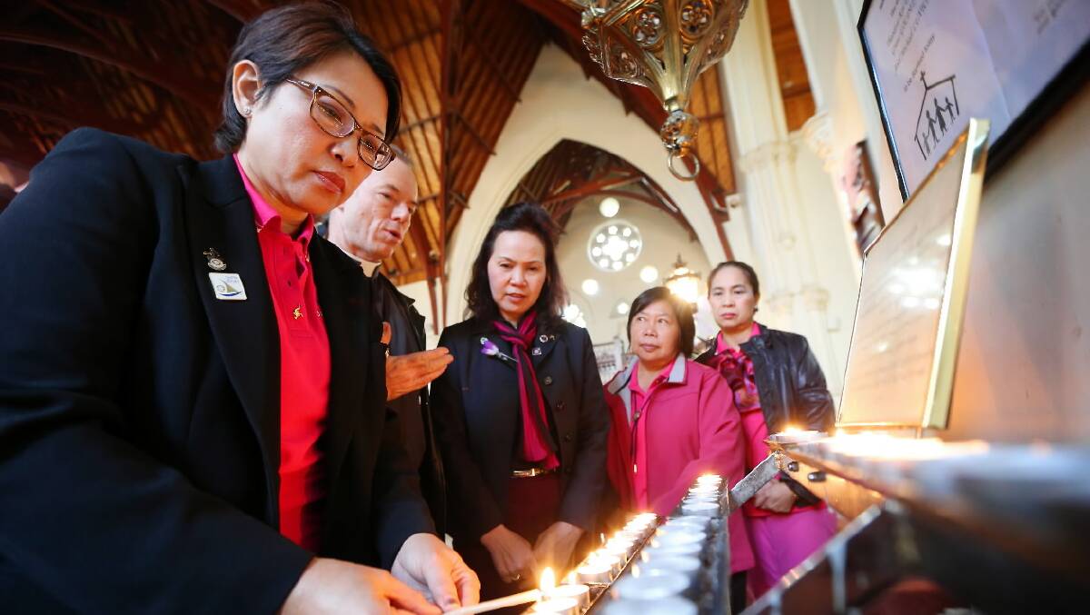 Thai Rotarian Dr Supattra Jittasathien prepares to light a candle and pray for peace in Thailand with Archdeacon Peter MacLeod-Miller as Thanita Sungboonyanithi, Supaporn Jansiriyotin and Nanthana Mangmi look on. Picture: JOHN RUSSELL
