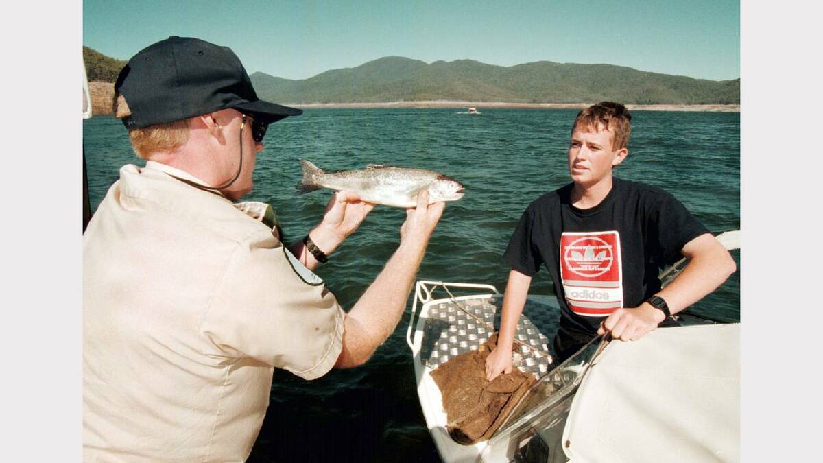 Fisheries and Wildlife Officer Greg Brodie checks a fish caught by Scott Lawry, 16, of Albury, who was fishing with his father, John, at Dartmouth Dam.