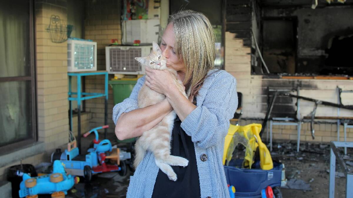 Natalie Regulski, pictured with her cat Nalah, frantically woke the nine other occupants of her Hibbett Crescent home yesterday morning after it was engulfed by flames and, below, a firefighter on the scene. Picture: BLAIR THOMSON
