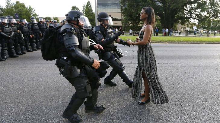 Police officers in riot gear face a woman in a dress during a Black Lives Matter protest in Baton Rouge. Photo: Jonathan Bachman / Reuters