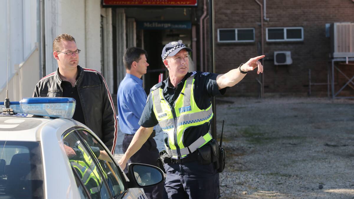 Local trader Ash Farrer speaks to police who are investigating the blaze. Picture: JOHN RUSSELL