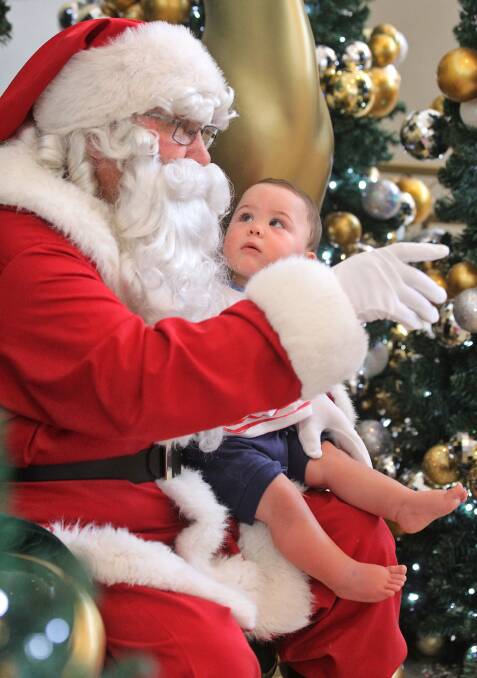Santa with Seth Vuiyale, 11 months, is intrigued by the man in the big red suit. 