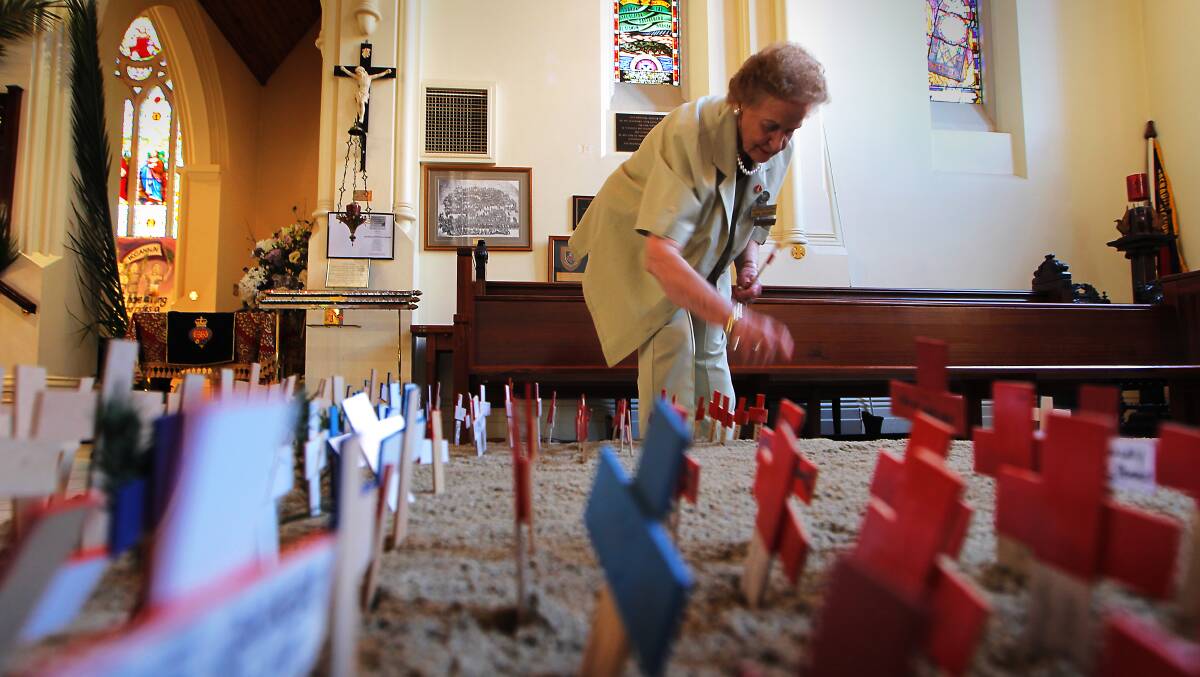 Albury and District War Widows Guild Club president Val Evans places crosses in memory of family members.