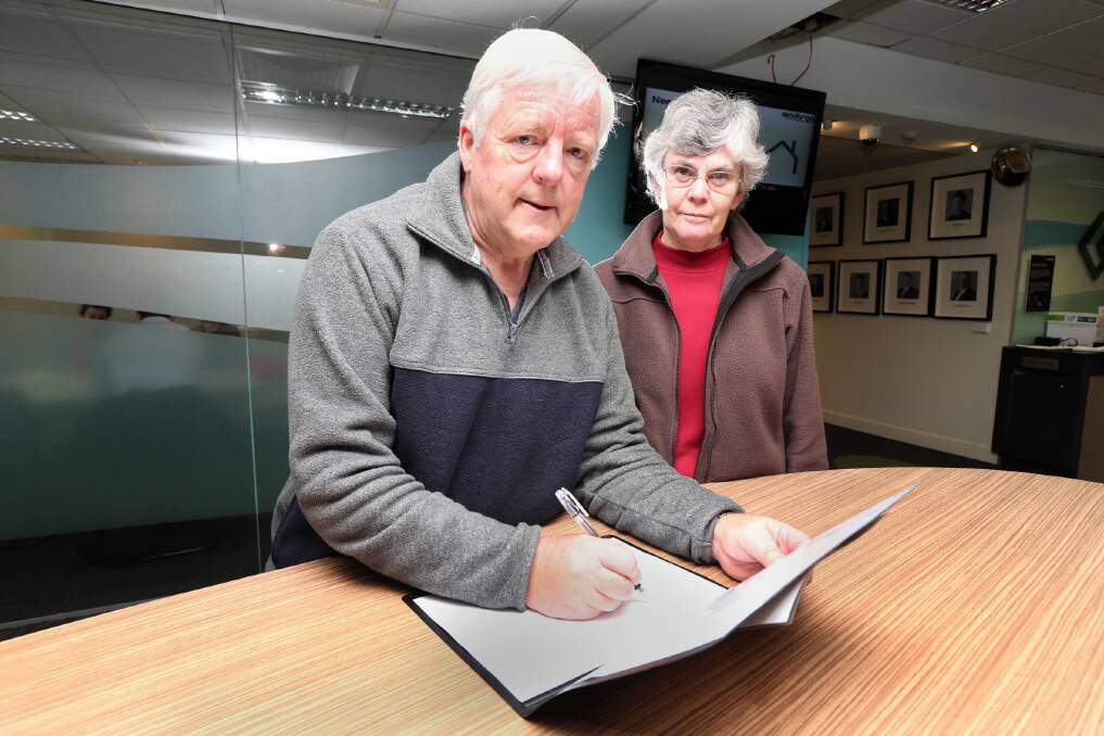Wodonga resident Lindsay Hanchett and his wife Carolyn sign the MH17 condolence book at Wodonga Council’s offices in Hovell Street yesterday. Picture: PETER MERKESTEYN
