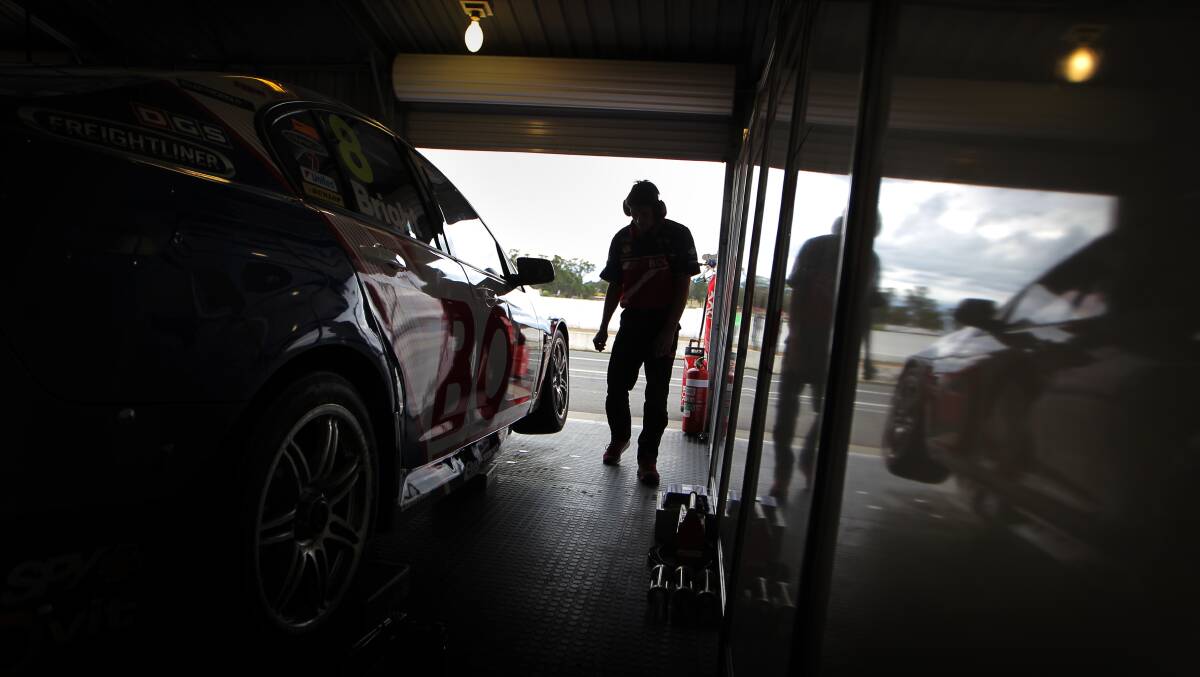 Team members work on Jason Bright's car in the Brad Jones Racing garage. 