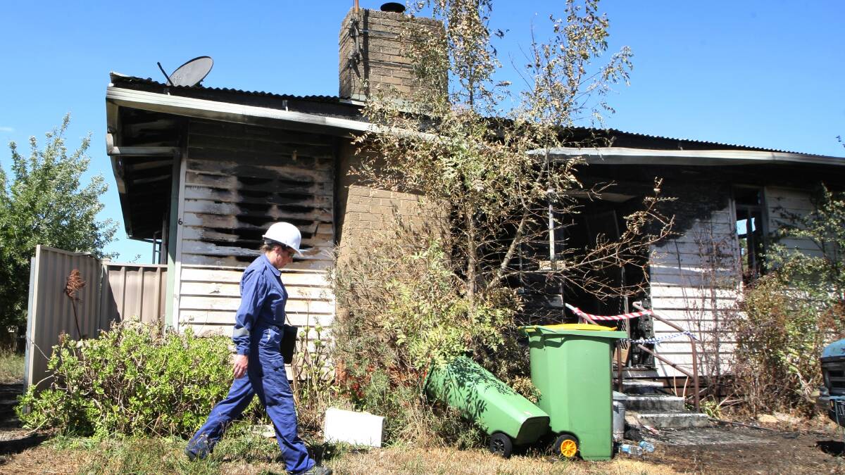 Forensic investigators look over the scene of a house fire on Le Couteur Avenue at Beechworth yesterday. 
