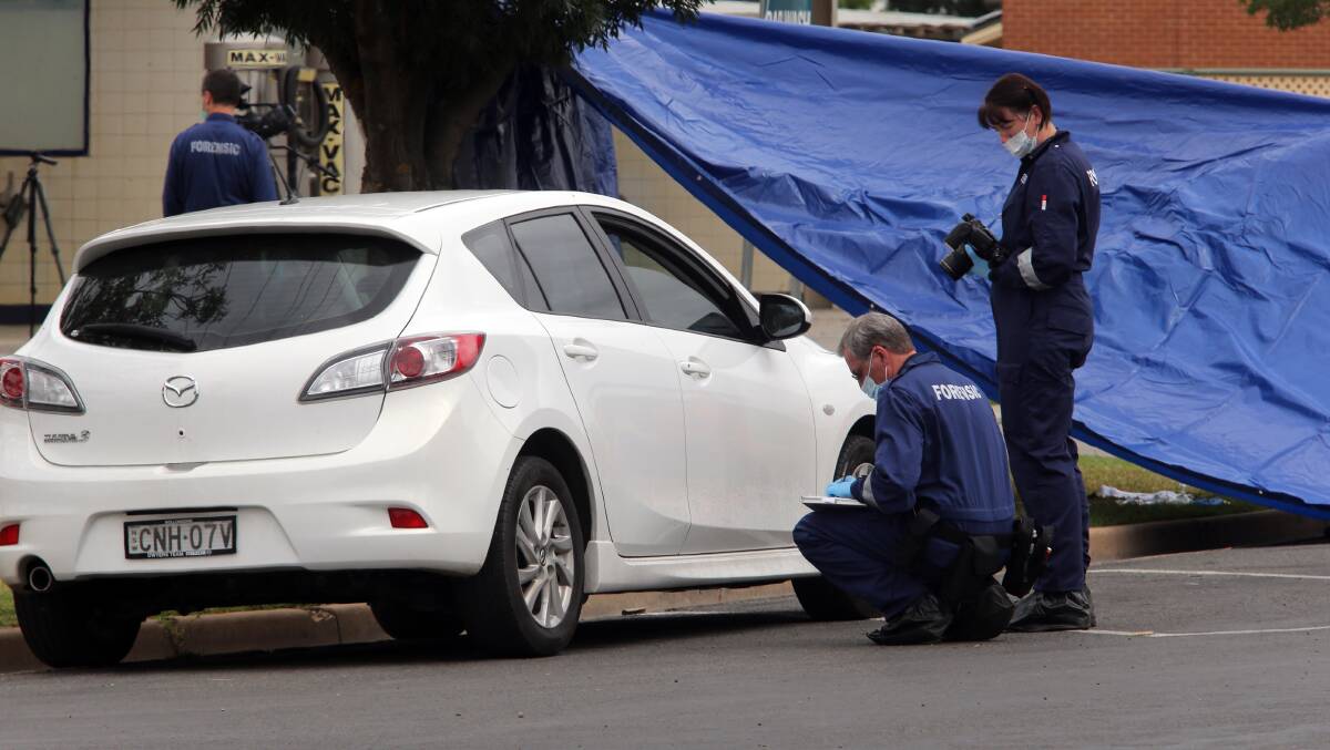 Police study a parked car at the scene.