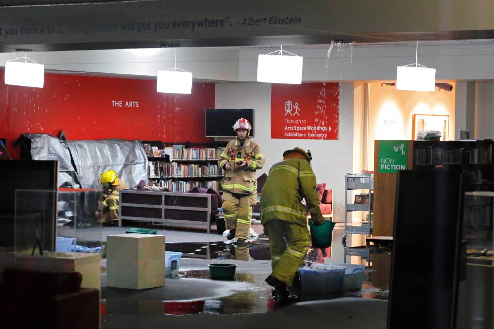 Firefighters inside the library the day rain leaked through. Picture: KYLIE ESLER