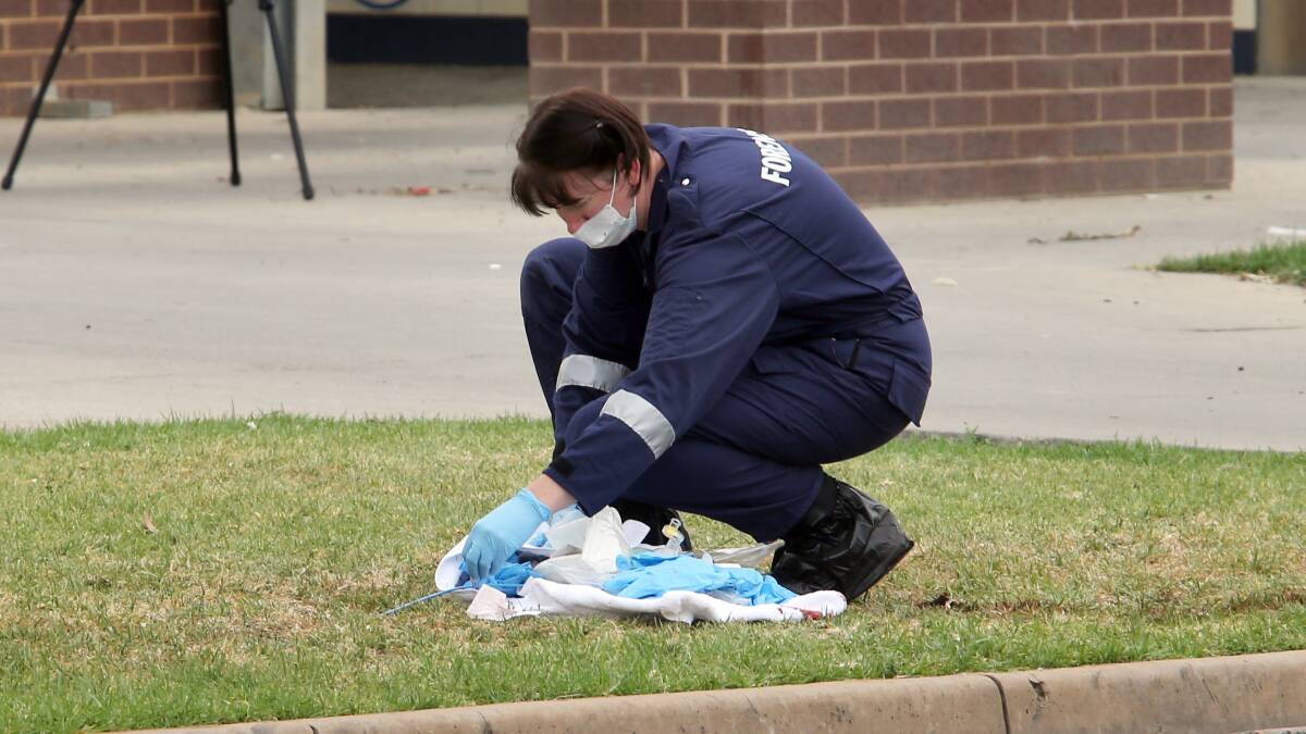A policewoman collects evidence at the scene.