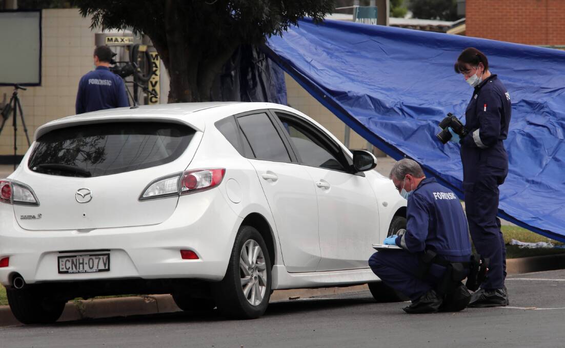 Police study a parked car at the scene of the crime. Pictures: PETER MERKESTEYN
