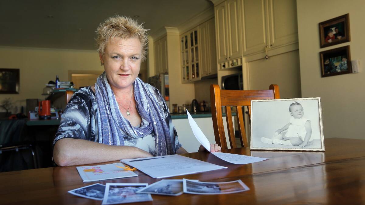 Helen Nicholson with her adoption papers and photos of herself as a child. Picture: TARA GOONAN