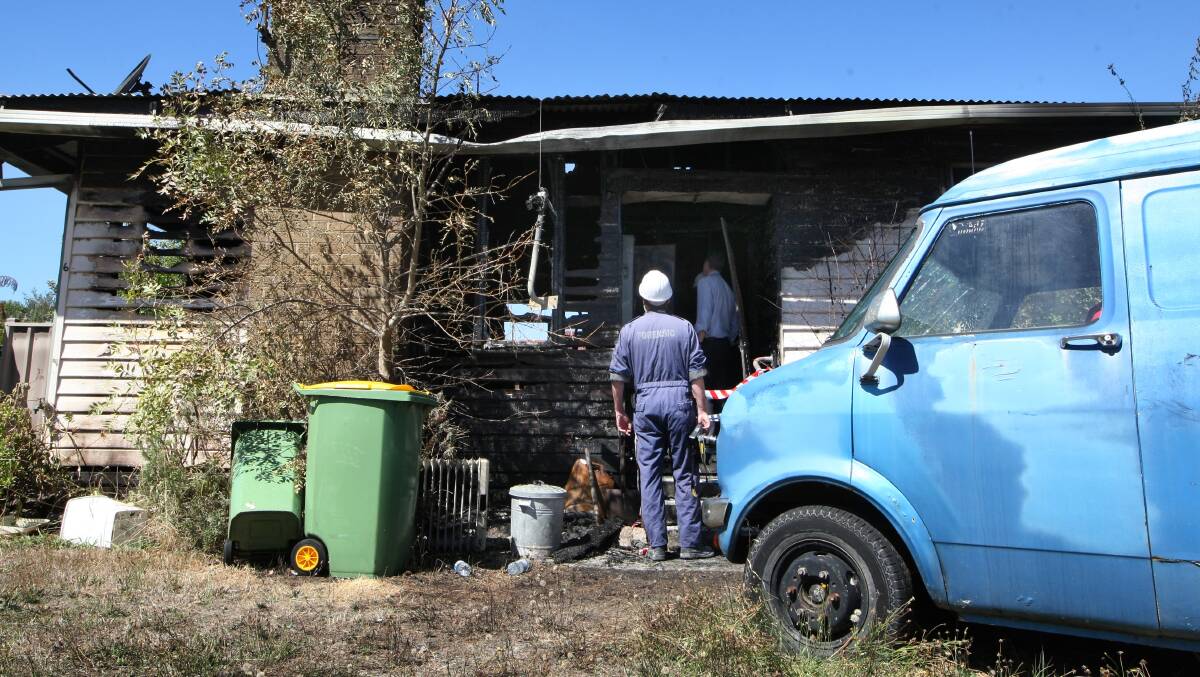 Forensic investigators look over the scene of a house fire on Le Couteur Avenue at Beechworth yesterday. Picture: DYLAN ROBINSON