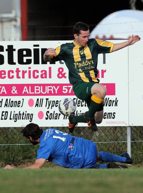 St Pats player Andrew Stevens jumps over Myrtleford's Michael Ferraro.