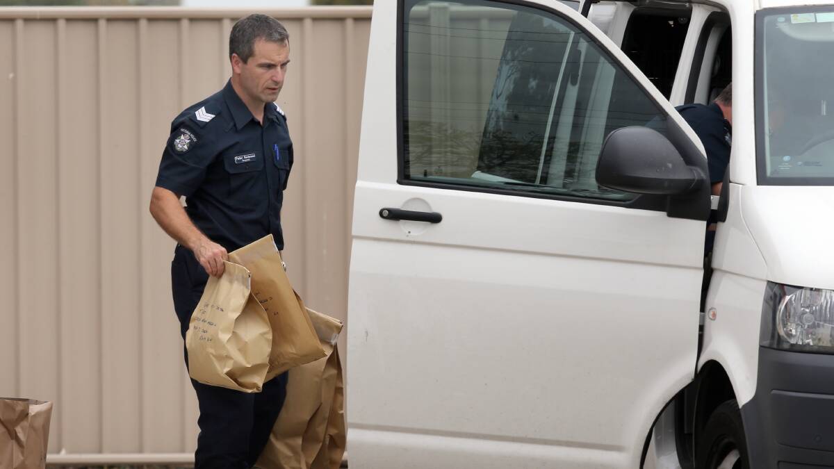 A policeman gathers the evidence collected at the scene of the stabbing.
