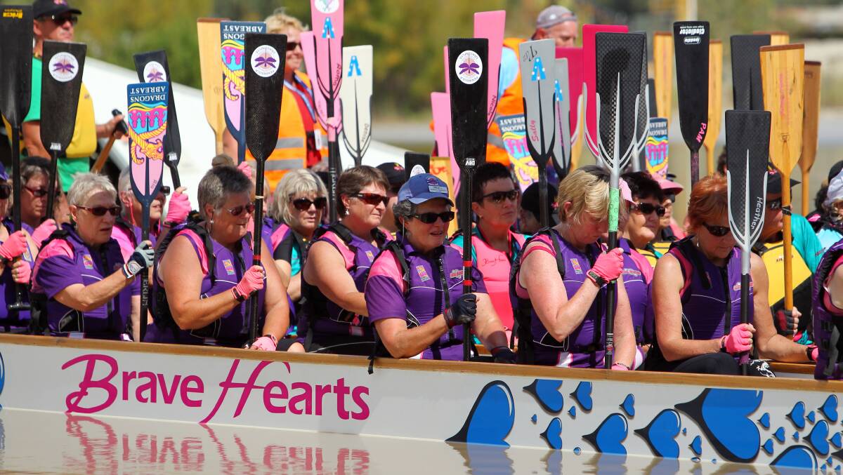  Competitors in the dragon boat racing pause and raise their paddles during a remembrance ceremony for those lost to cancer.