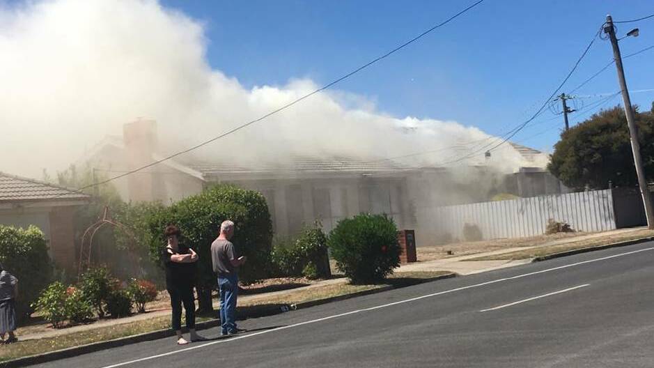 Neighbours watch on as smoke billows out of the house. Picture: Anna Law.