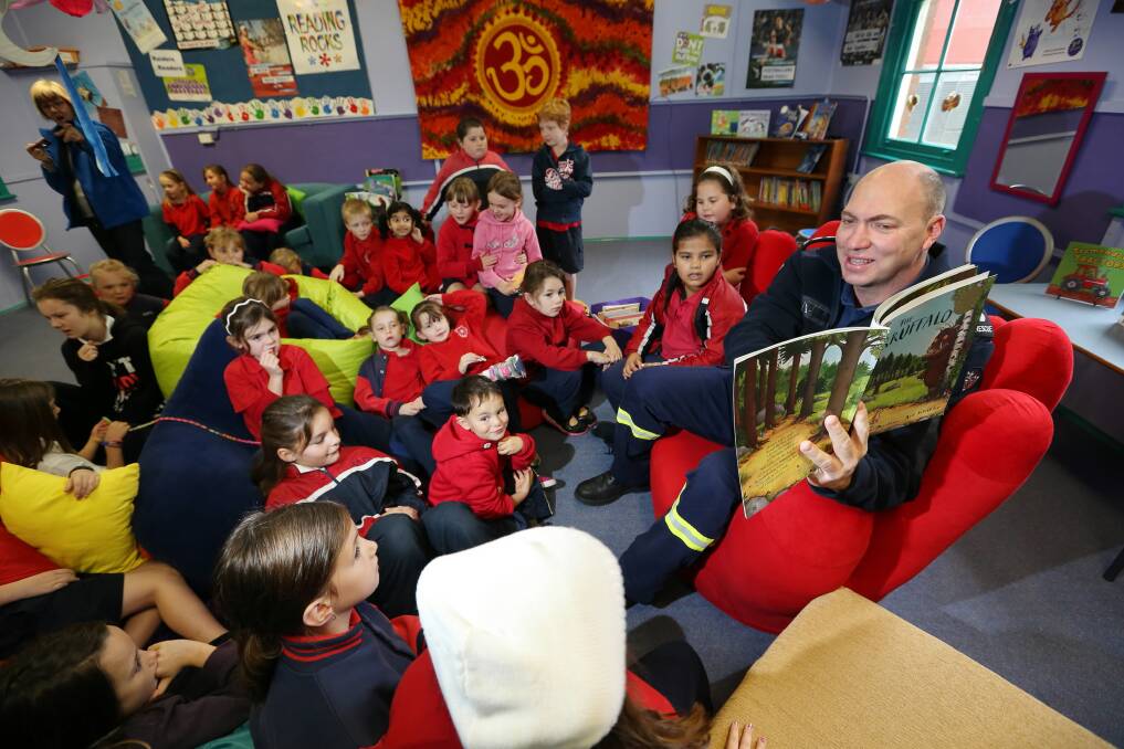 Everybody reads, not just teachers ... Dean Campbell, station officer at Albury Central Fire Station, shares a book with Albury North Public School students. Picture: MATTHEW SMITHWICK