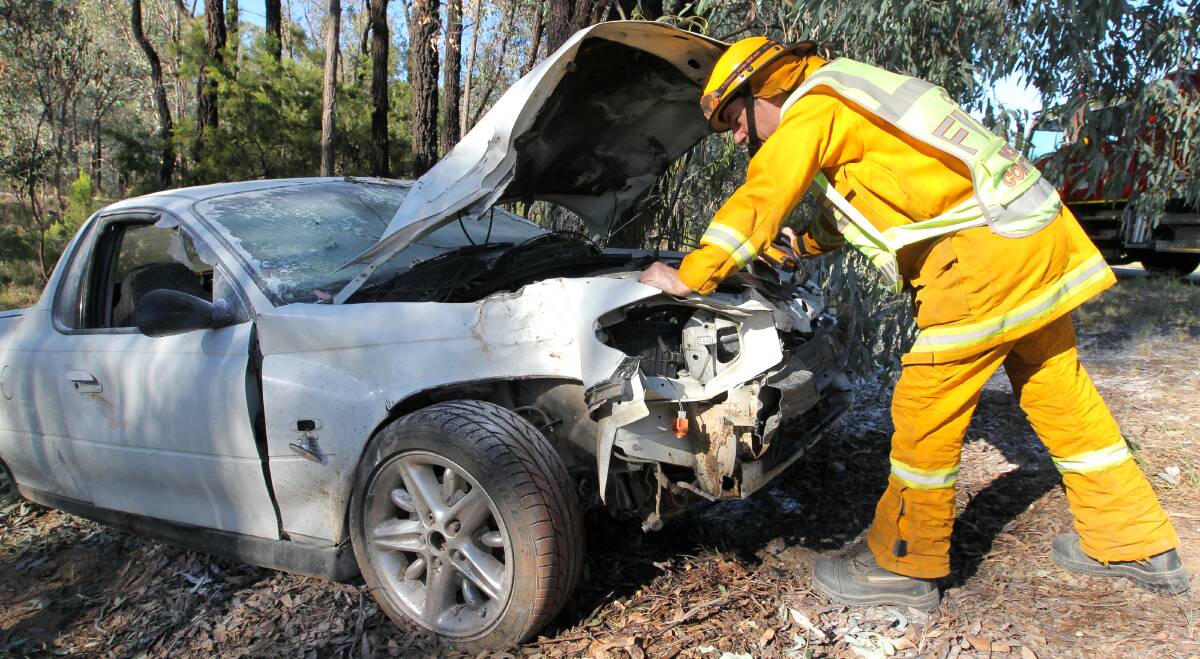 SMASHED: Chiltern firefighter Ian Trewhella with the damaged vehicle on the side of the Hume Freeway on Tuesday. Pictures: BLAIR THOMSON