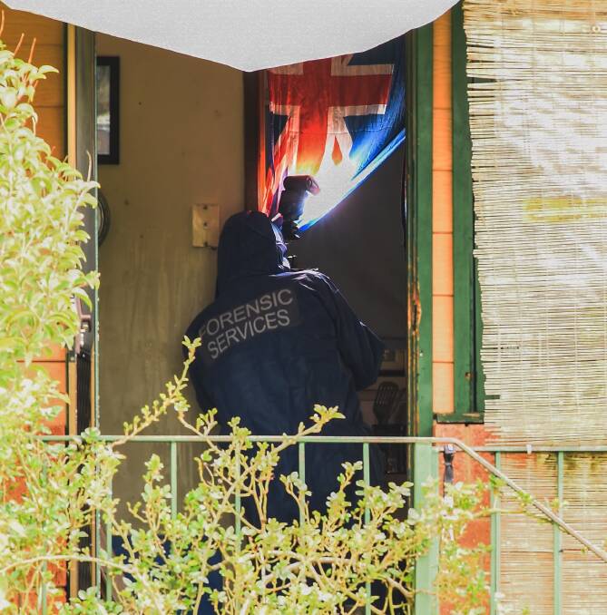 GATHERING EVIDENCE: A forensic officer takes photos inside the man's home on Thursday morning. They spent several hours gathering evidence at the property. Pictures: MARK JESSER