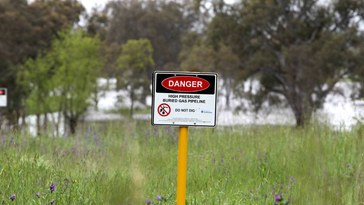 FEARS: Floodwaters can be seen behind signs warning about the high-pressure gas line. 