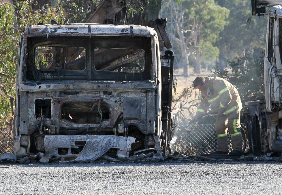 GUTTED: A firefighter with one of the four destroyed vehicles at JJ Richards in Wodonga on Monday morning. Picture: BLAIR THOMSON