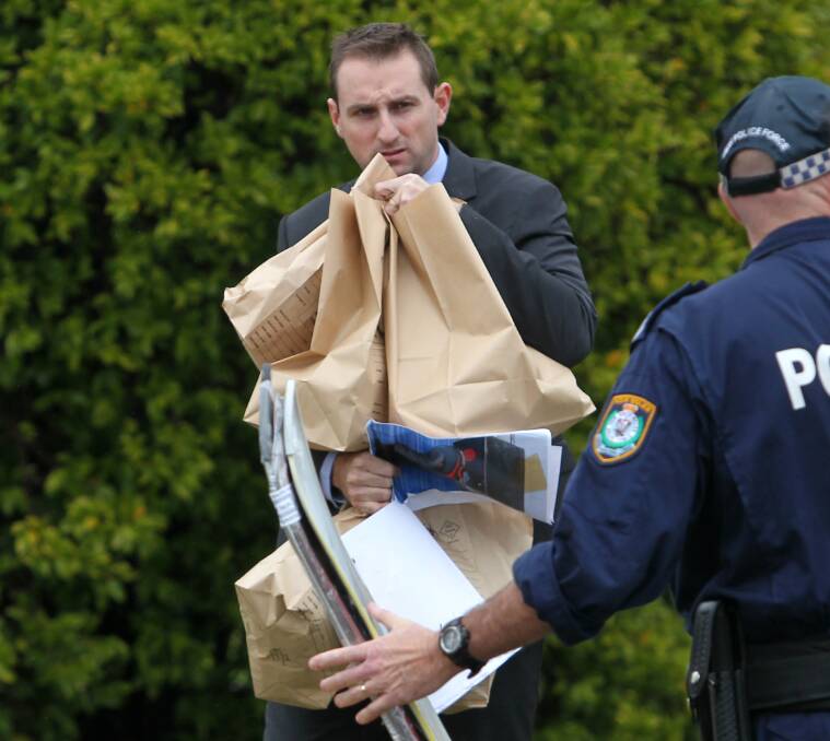 SEIZURE: An Albury officer removes a bundle of evidence bags from the home. Picture: BLAIR THOMSON