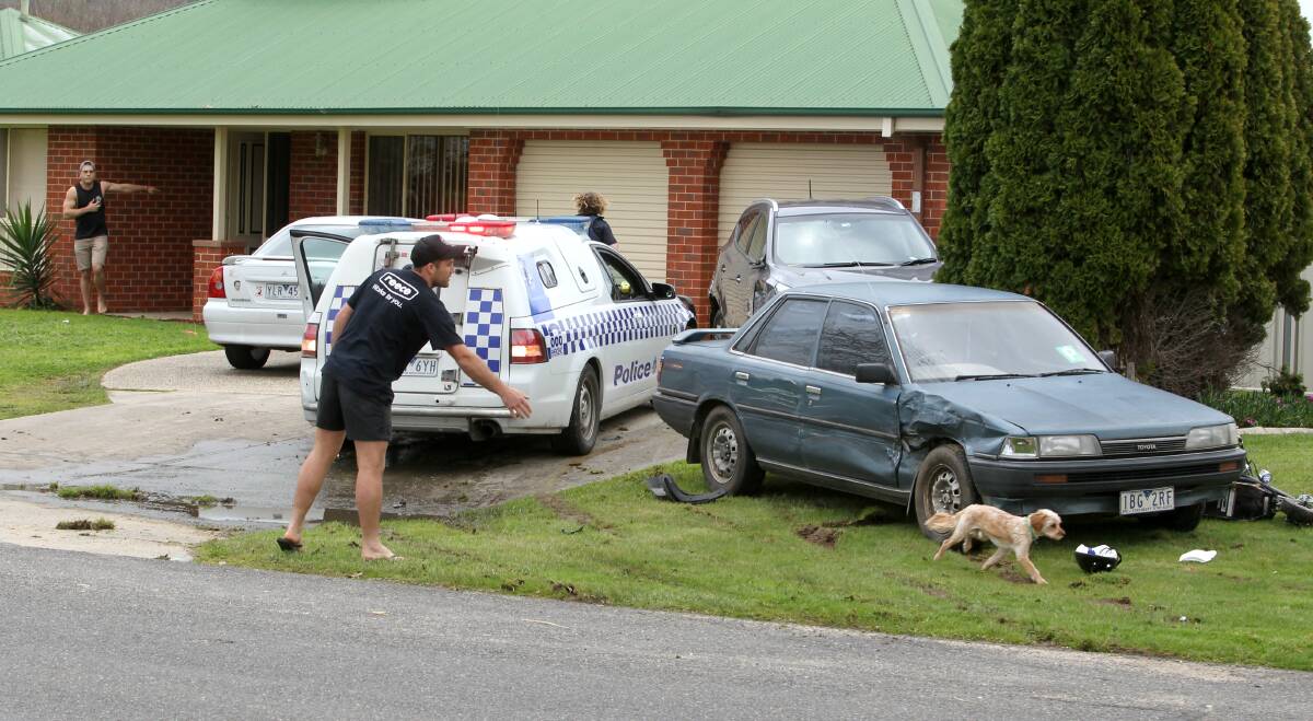 SMASHED: A dog runs from a home moments after the stolen vehicle crashed. A man, pictured top left, points to where the offender ran. 