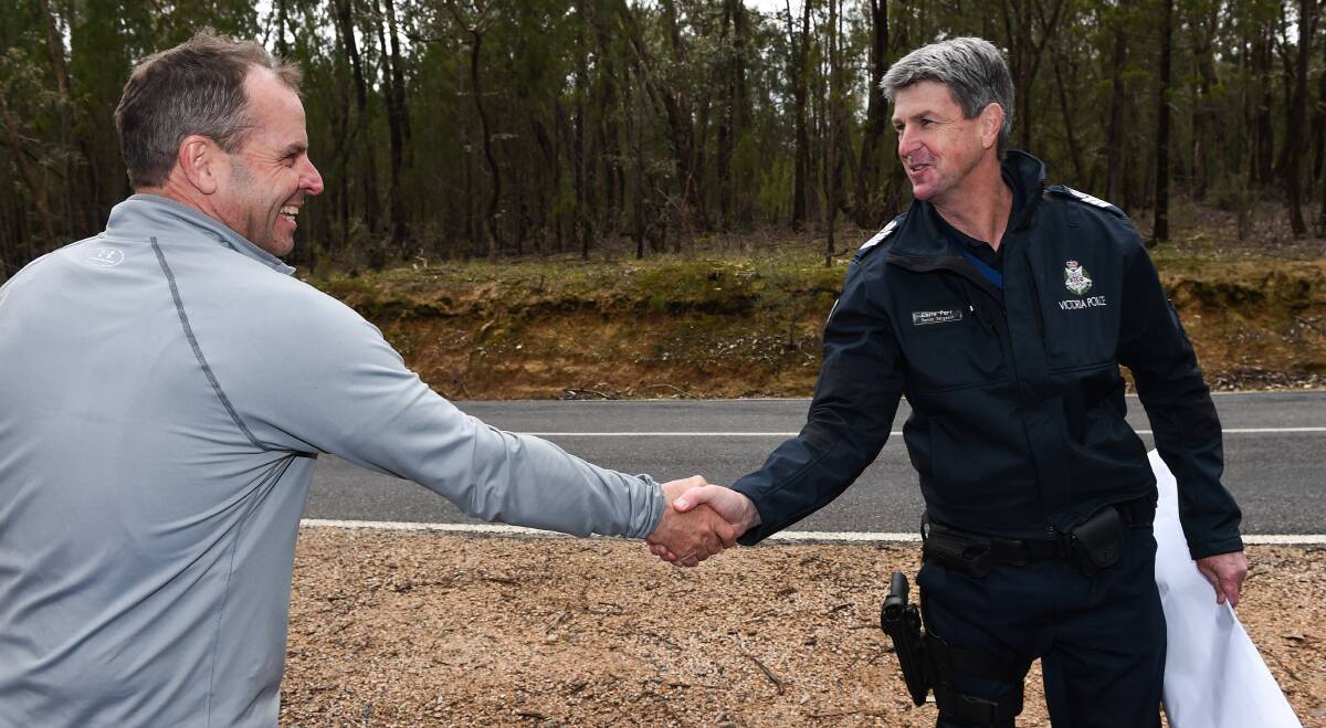RESCUER: John McLennan is thanked by Senior Sergeant Chris Parr for helping to find Ben Dean on Thursday. Mr McLennan had jumped on his motorbike to join the search after reading about it on Facebook. Picture: MARK JESSER