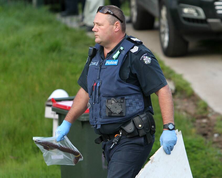 SEIZURE: Sergeant Mick Savage removes an imitation gun from the Wodonga home during Thursday's raid. A Holden Commodore and range of other items were also seized. Pictures: BLAIR THOMSON