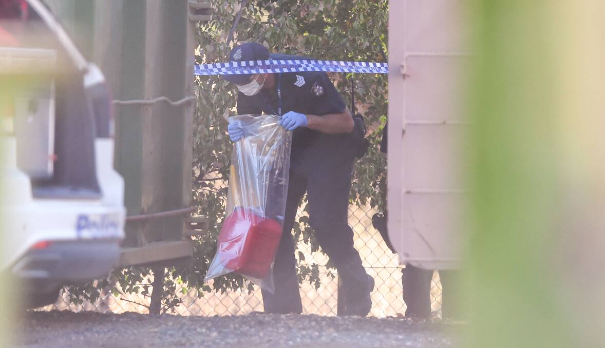 EVIDENCE: A crime scene officer removes a red petrol container from the business. Police spent several hours examining the area. Picture: MARK JESSER