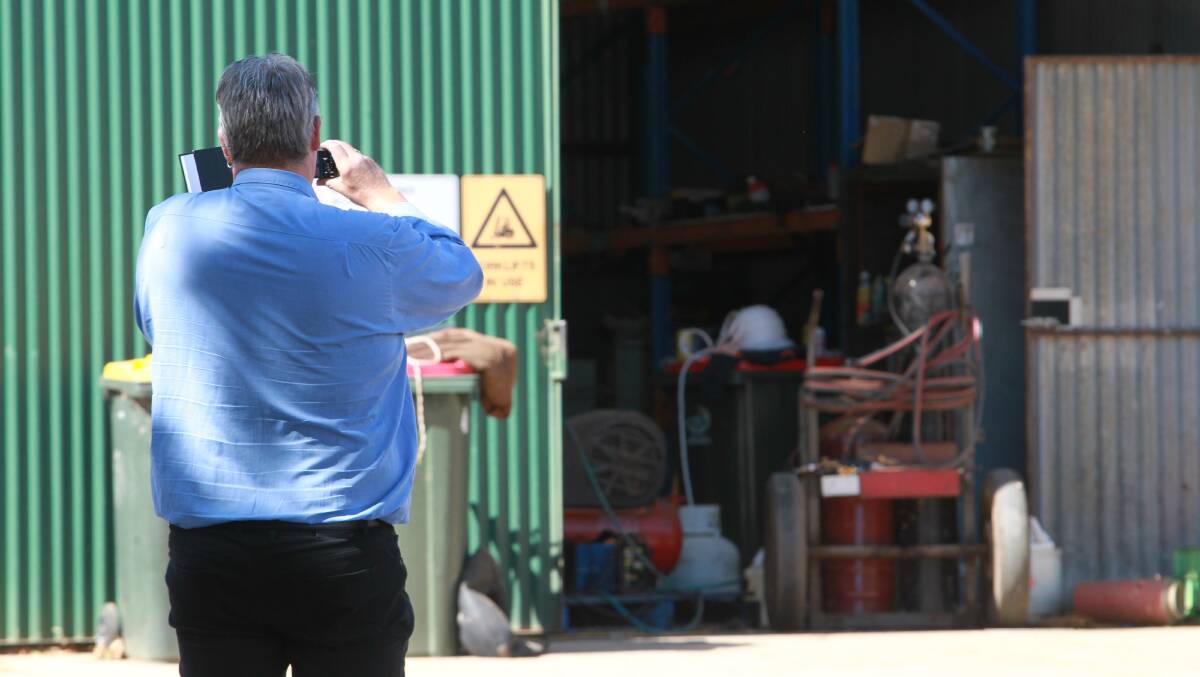 INJURED: A WorkSafe employee takes photos of a shed where a woman lost her arm on Thursday. Picture: BLAIR THOMSON