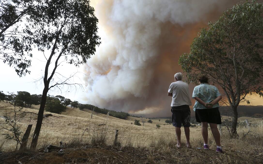 CONCERNING SIGHT: Two people watch the fires from the top of the Indigo Valley on December 20 last year. 