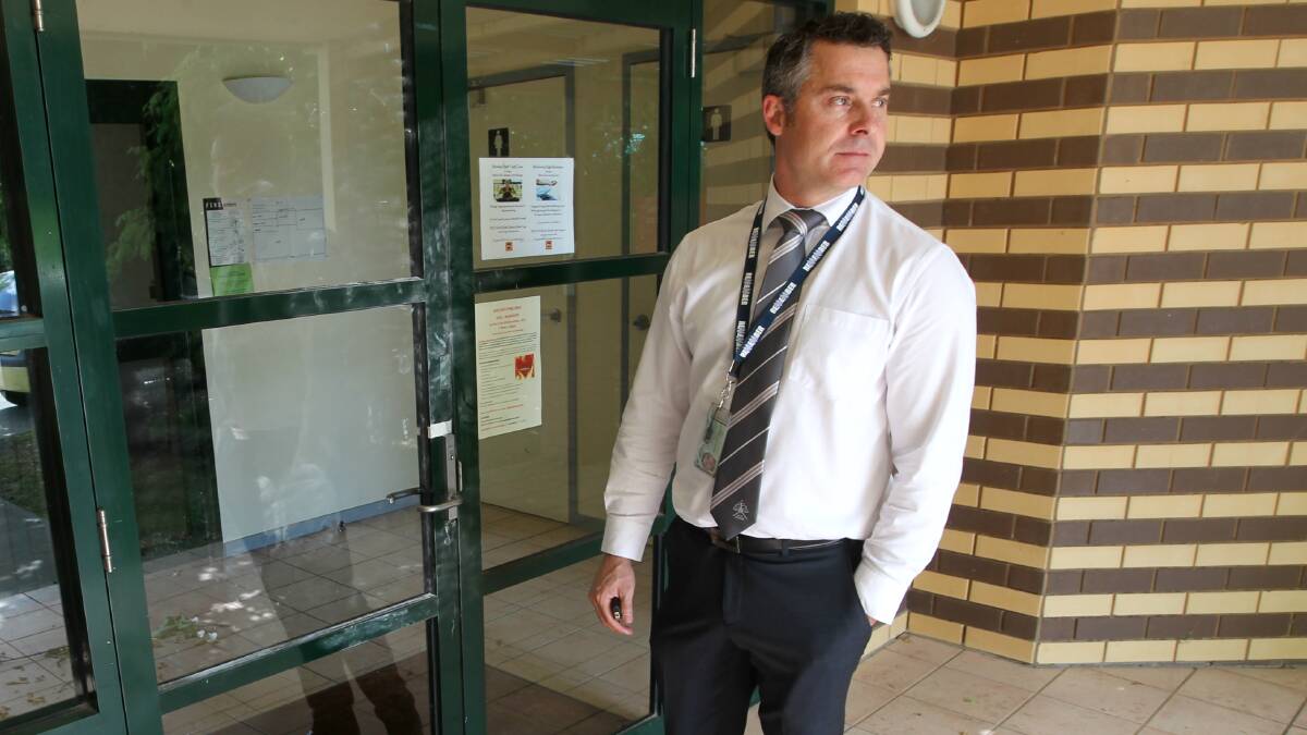 TARGET: Detective Sergeant Graeme Simpfendorfer at the scene of the break-in on Watson Street. One thief left a buttock print on the glass door. Picture: BLAIR THOMSON