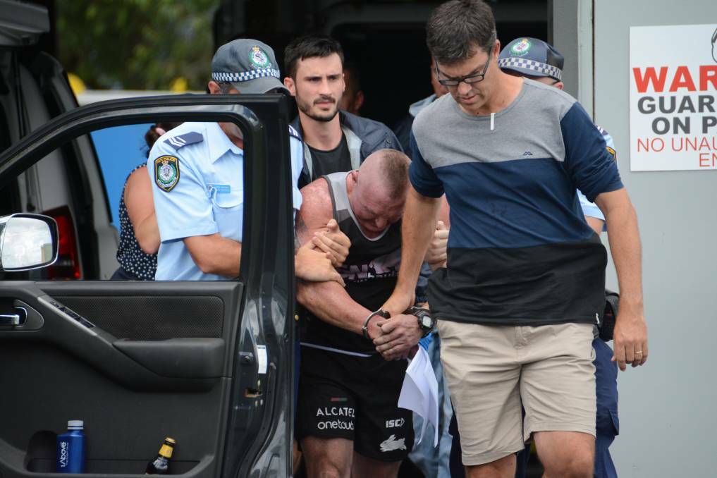 Retired Taree rugby league player and local businessman Dean Simpson being led away following his dramatic arrest by Manning-Great Lakes police.