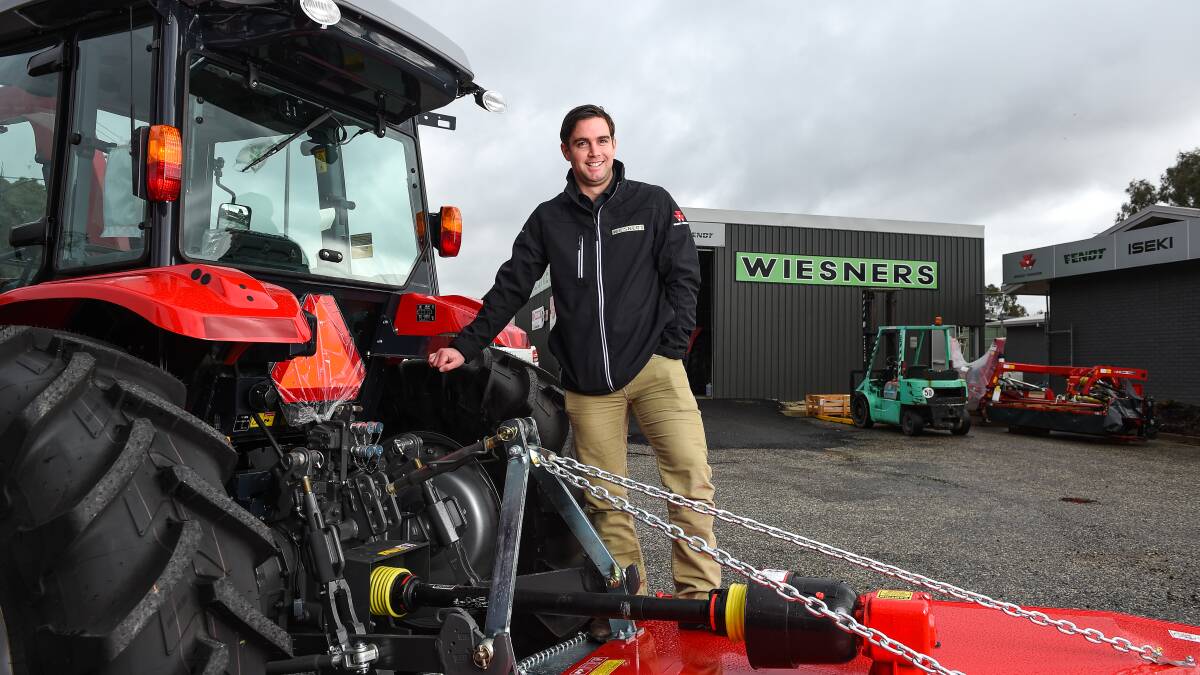 New era: Sales member Ash Irvine with one of the many brands of tractors available from Wiesners' new Wodonga centre, to be officially opened next week. Picture: MARK JESSER